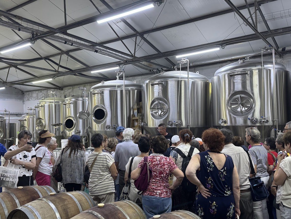 קבוצת מבקרים בסיור במזקקת פפא, מול מכלי התסיסה